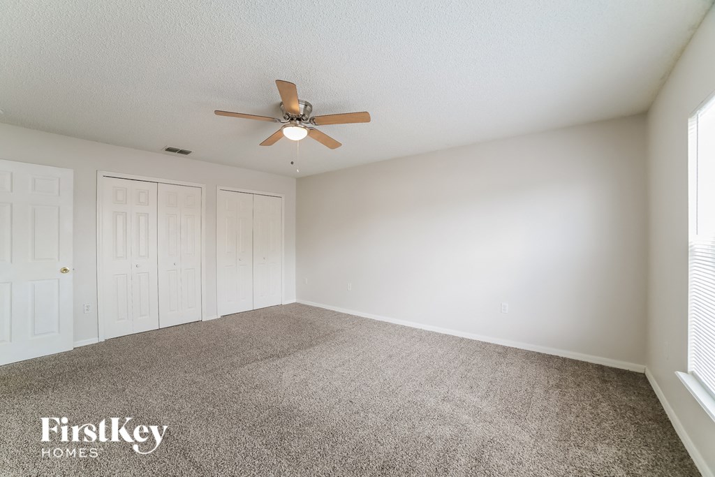 a spacious living room with carpet and a ceiling fan
