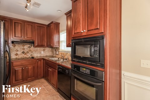 A kitchen with brown cabinets and black appliances.