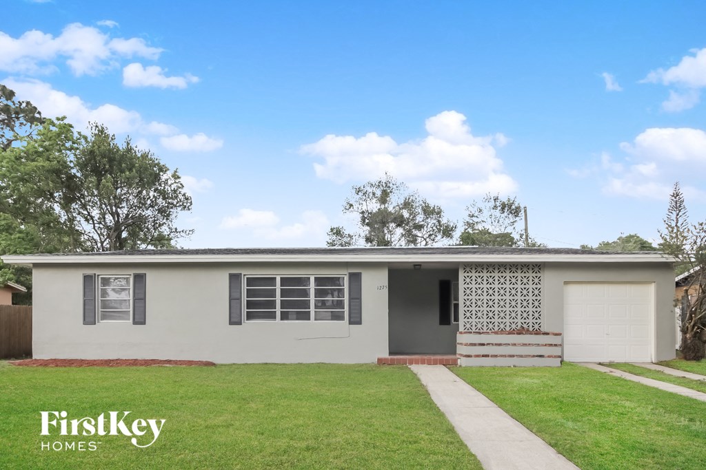 A house with a white garage door and a brick pillar.