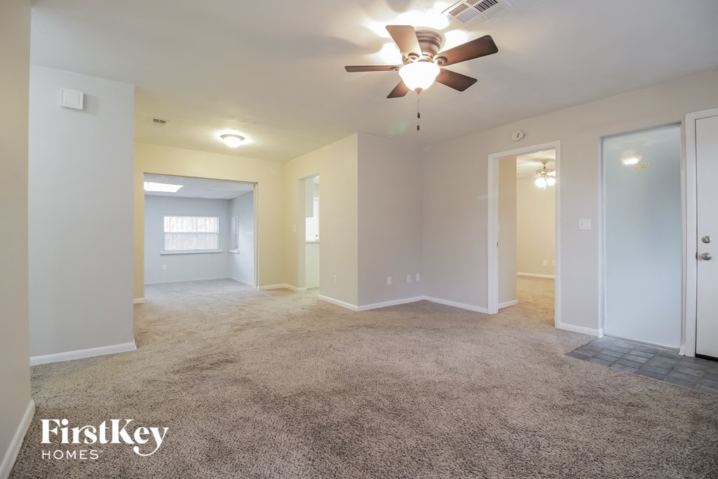 A spacious room with a ceiling fan and carpeted floor.