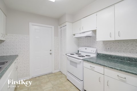 A kitchen with white cabinets and a white stove top oven.