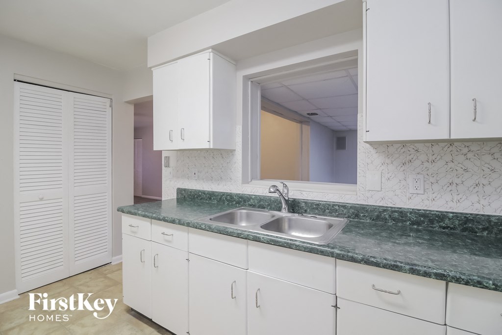 A kitchen with white cabinets and a green marble countertop.