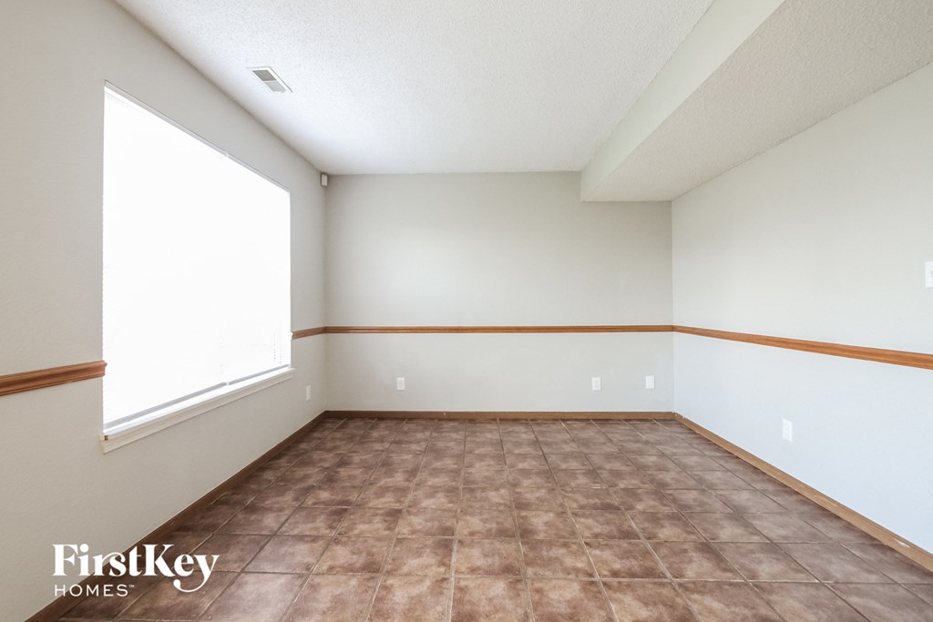 the living room of this home has a large window and beige and brown tile