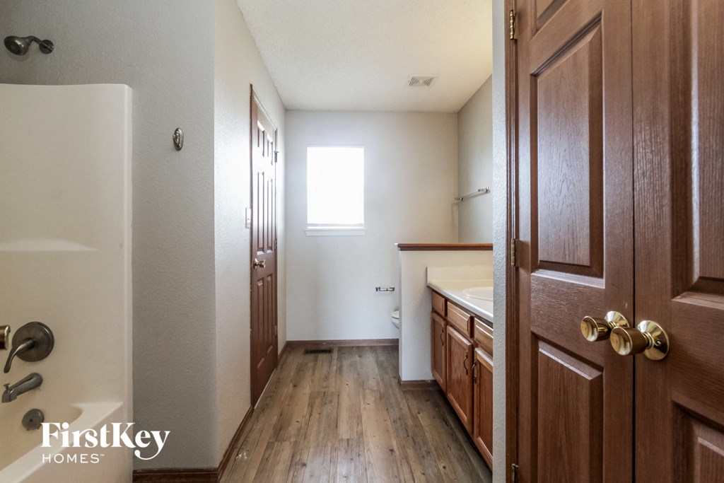 a bathroom with wooden floors and wooden cabinets and a sink