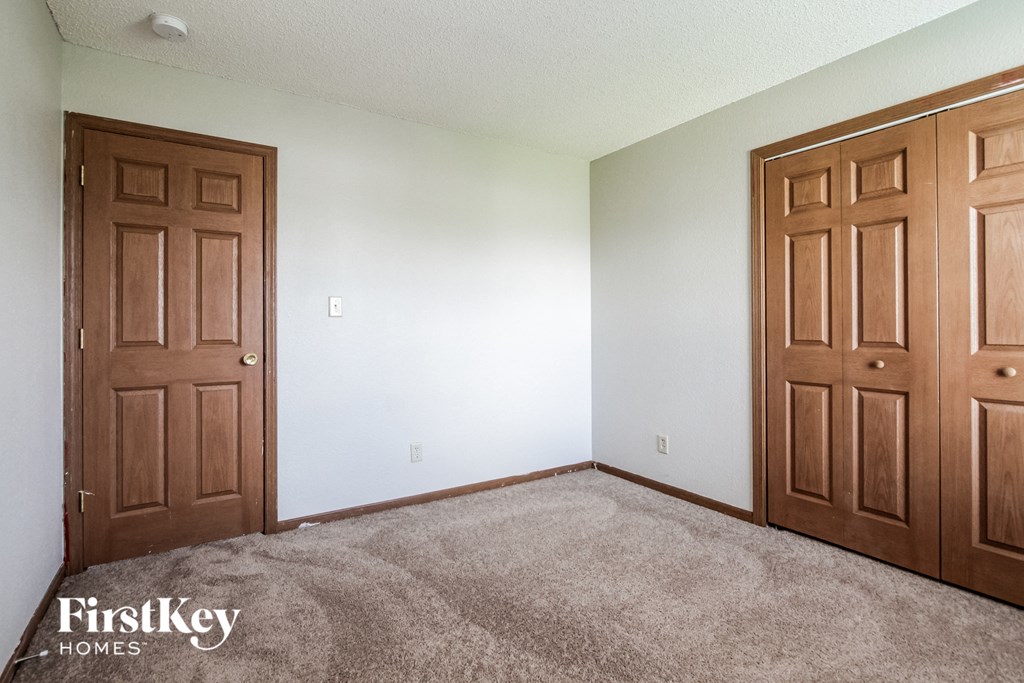 a bedroom with two doors and a carpeted floor
