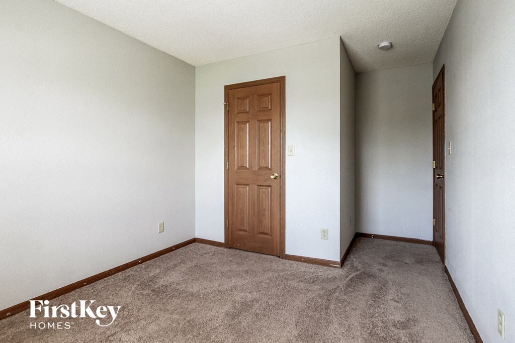a bedroom with a carpeted floor and a wooden door