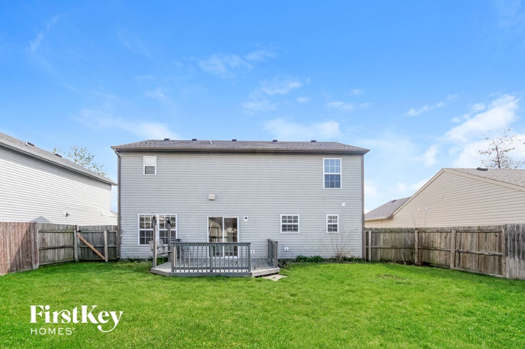 the back of a white house with a yard and a wooden fence