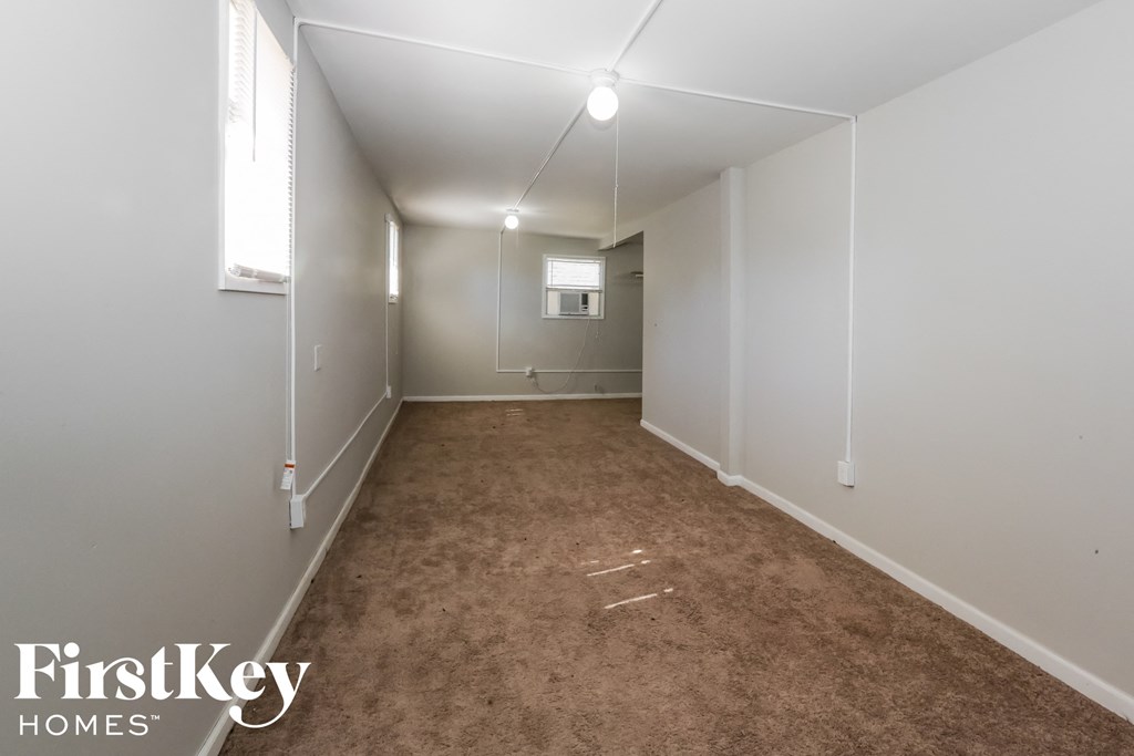 a room with a carpet and white walls and a window