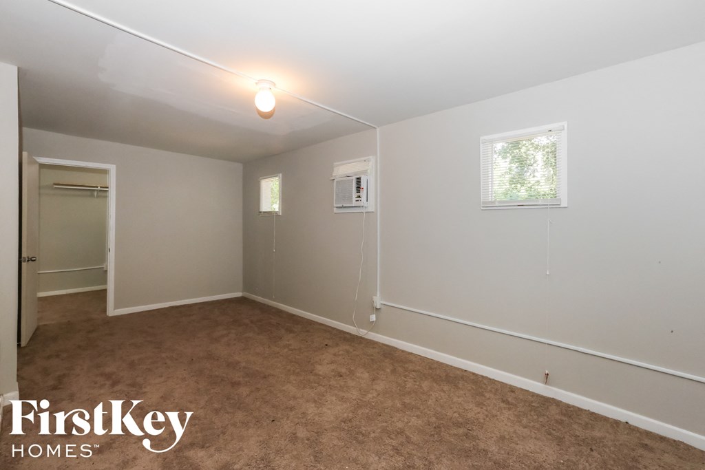a bedroom with a carpeted floor and a white wall and a window