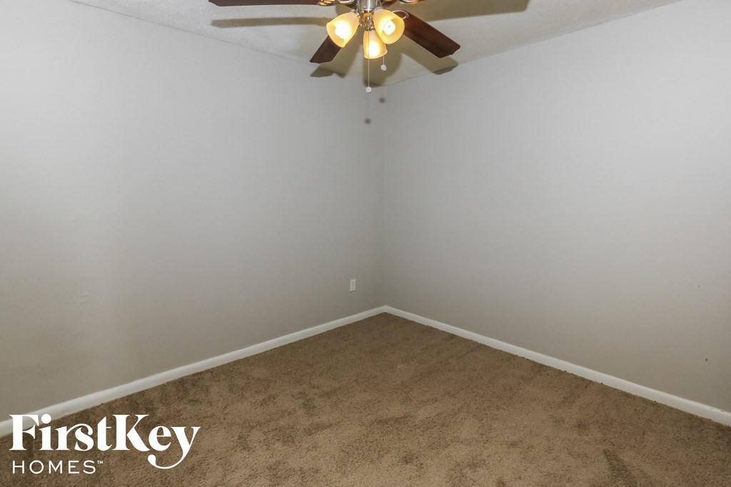 a empty room with a ceiling fan and a carpet