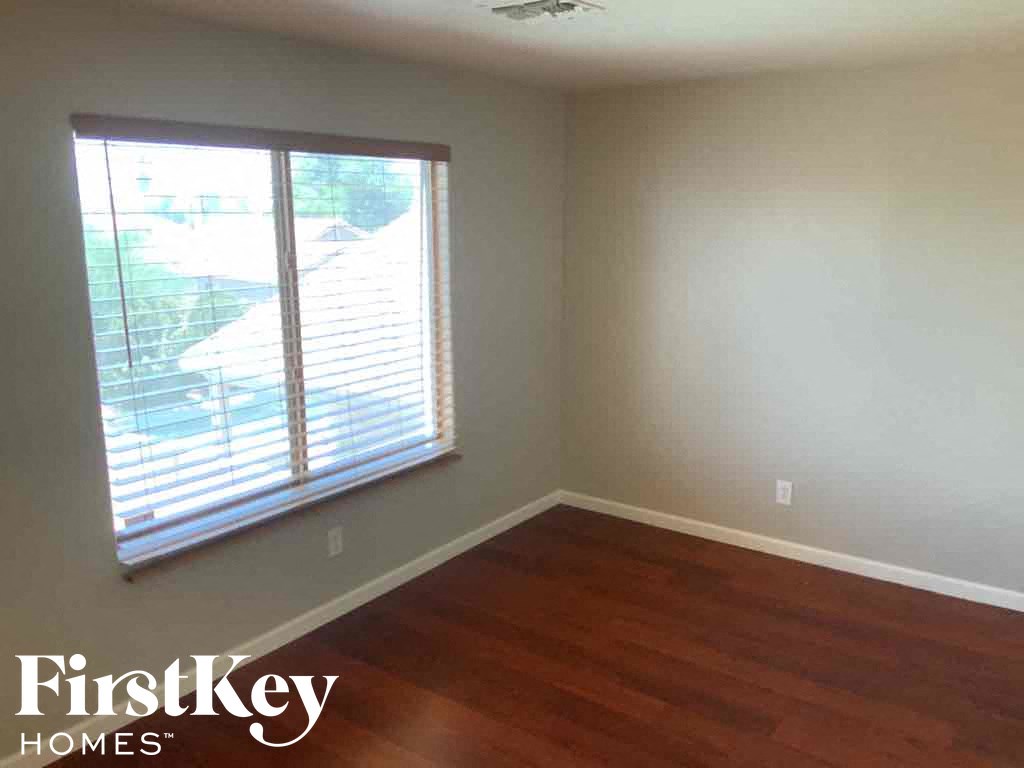 A room with wooden floors and a window with blinds.