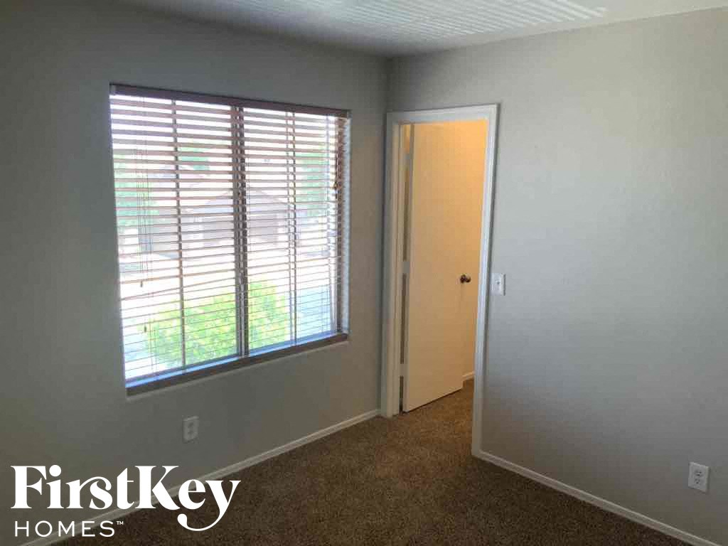 A room with a carpeted floor, a door, and a window with blinds.
