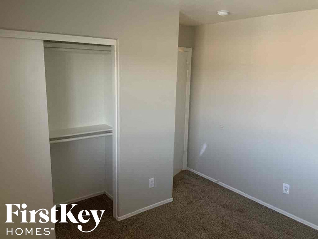 A carpeted room with a closet and a FirstKey Homes logo.