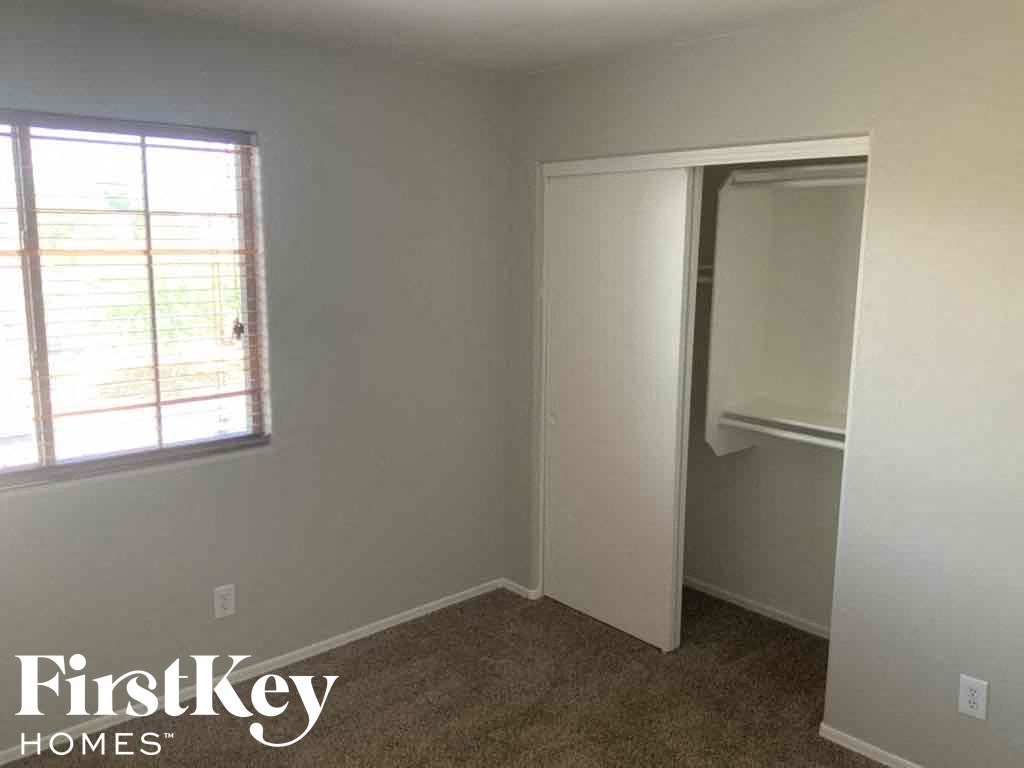A room with a carpet floor, a window, and a door.