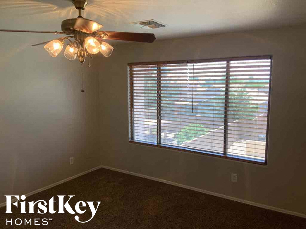A room with a ceiling fan and a window with blinds.