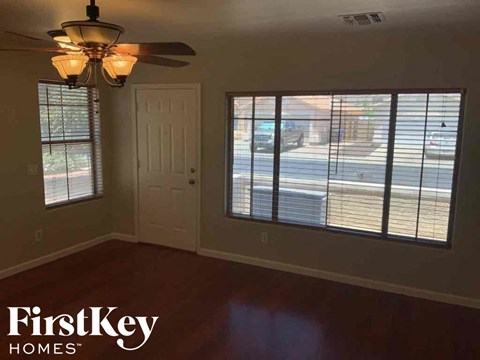 A room with a ceiling fan and a view of the street through the window.