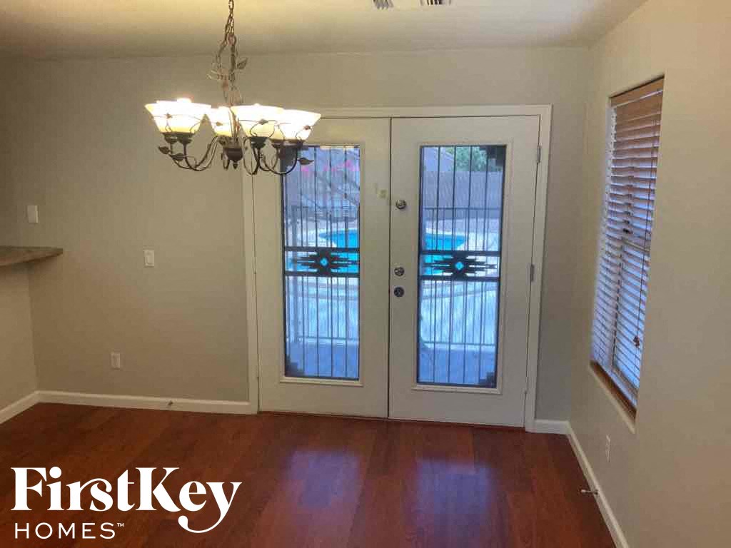 A room with a chandelier and a view of a carport through the sliding glass doors.