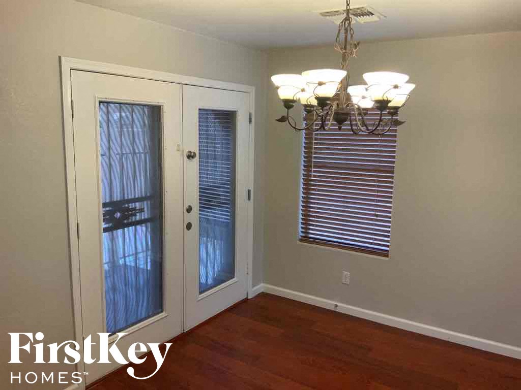 A room with a chandelier, a door with a glass panel, and a wall-mounted light switch.