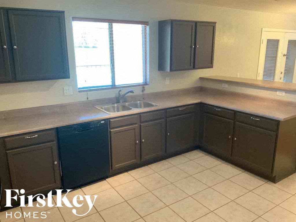 A kitchen with dark cabinets and a tiled floor.
