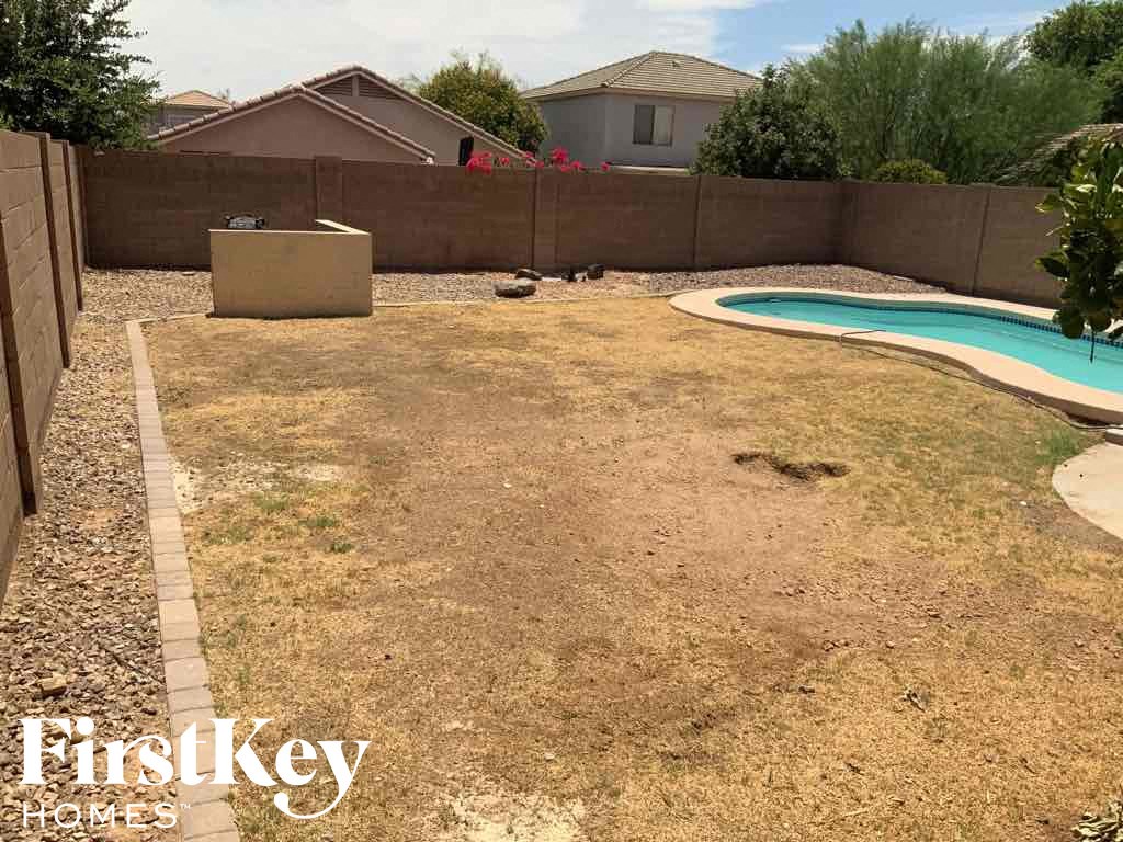 A backyard with a pool and a fence.