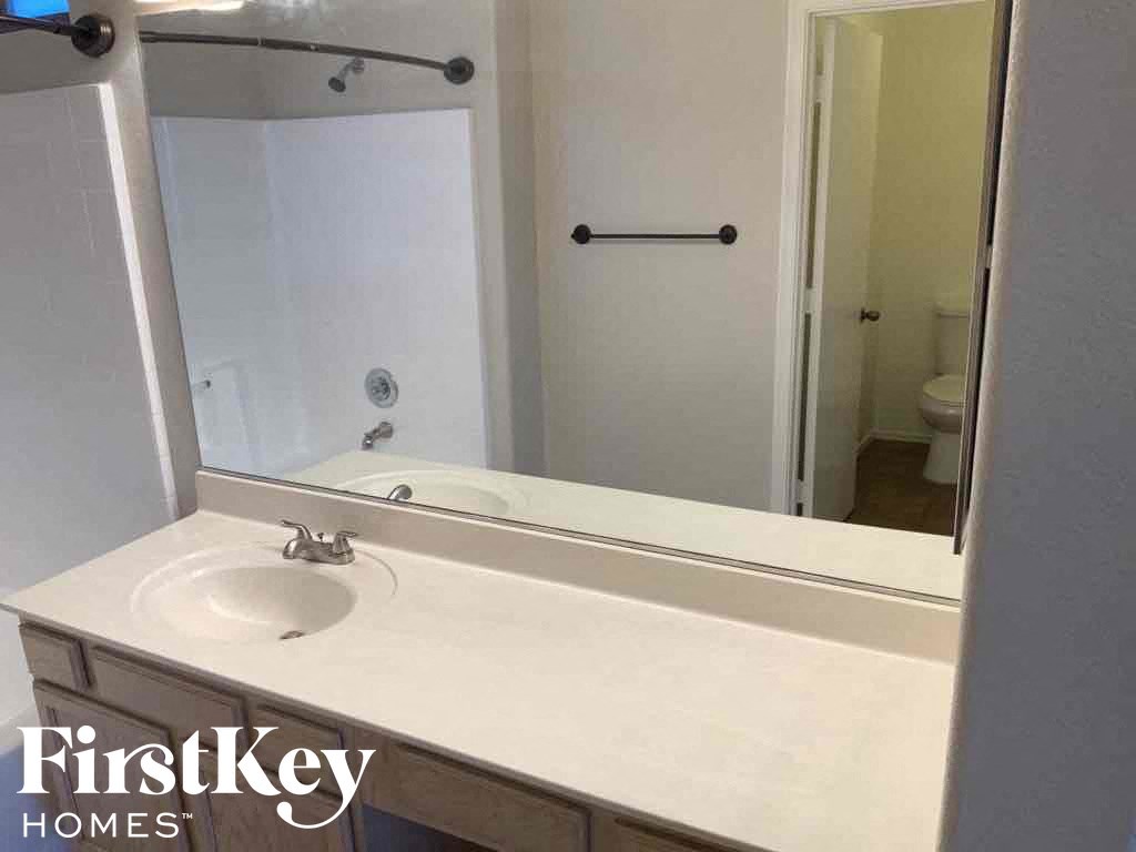 A bathroom with a white sink and mirror.
