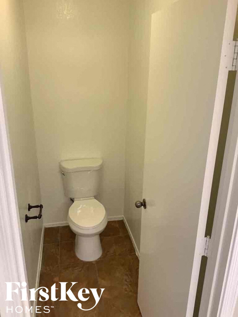 A white toilet in a small bathroom with FirstKey Homes written on the bottom.
