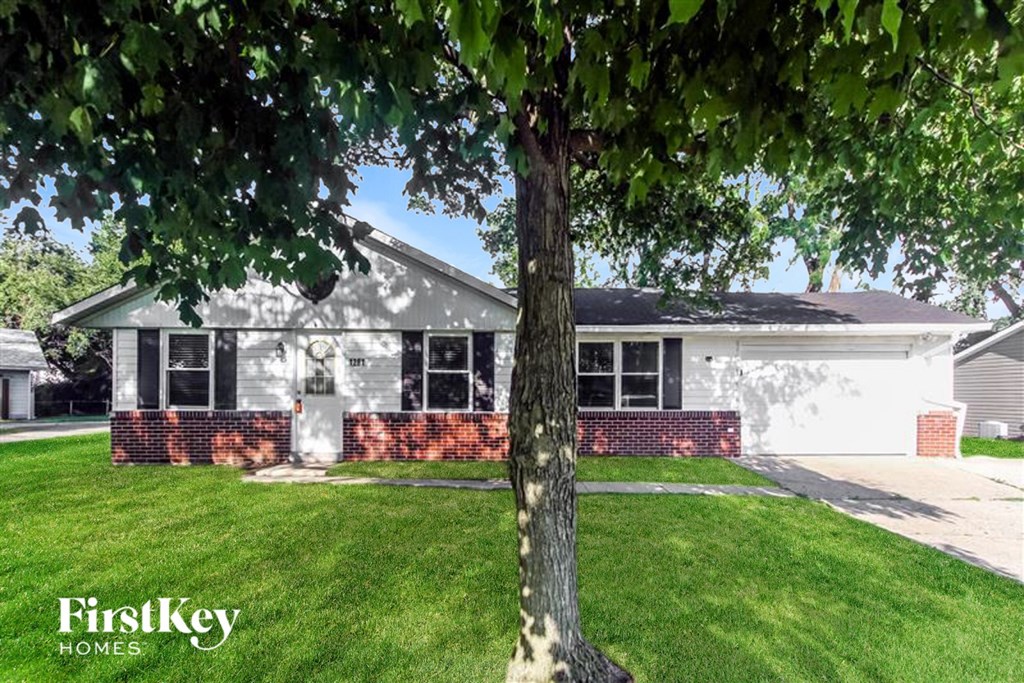 A tree stands in front of a house with a sign that says FirstKey Homes.