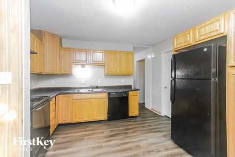 A kitchen with wooden cabinets and a black fridge.