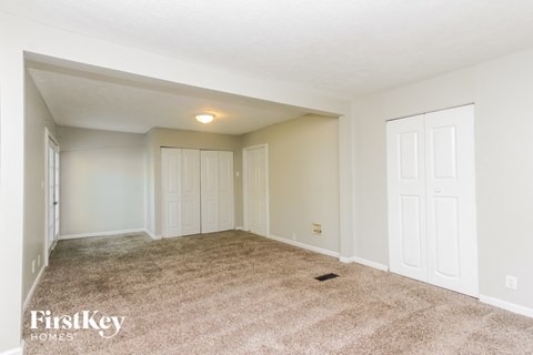 A spacious room with a carpeted floor and white walls.