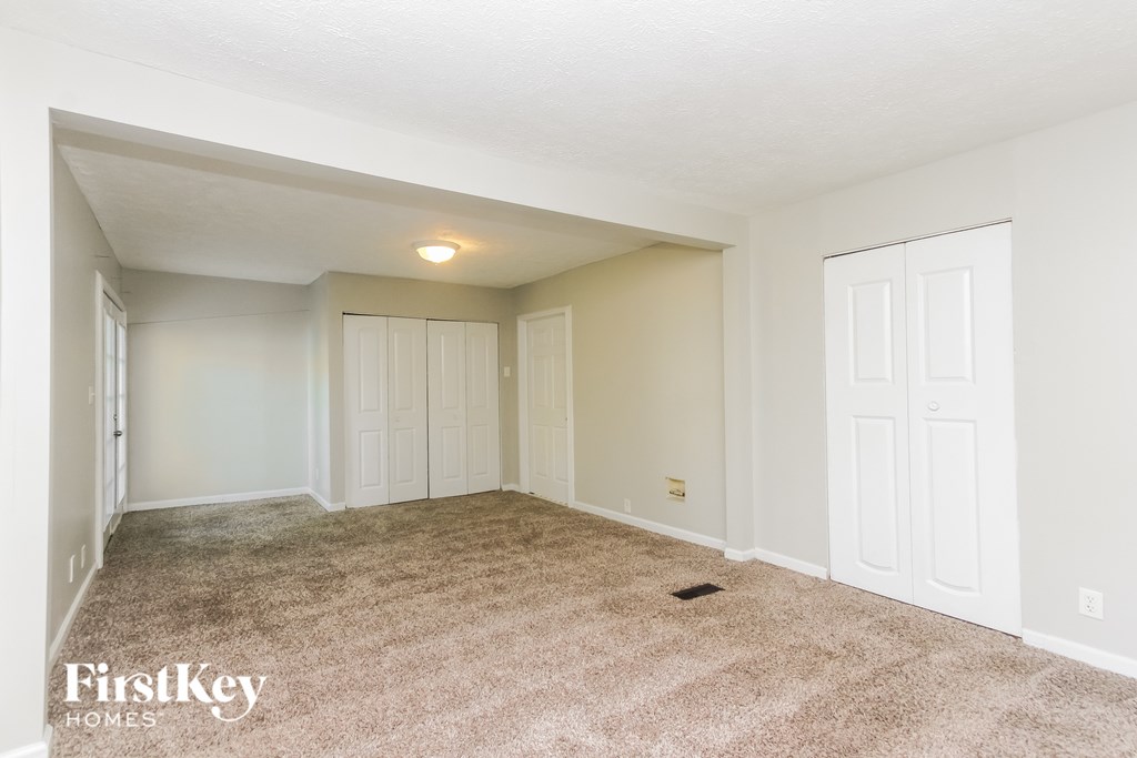 A spacious room with a carpeted floor and white walls.