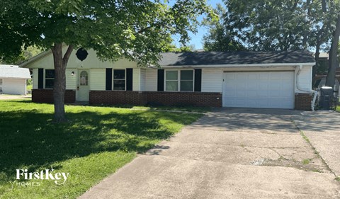 a white house with a white garage door and a tree