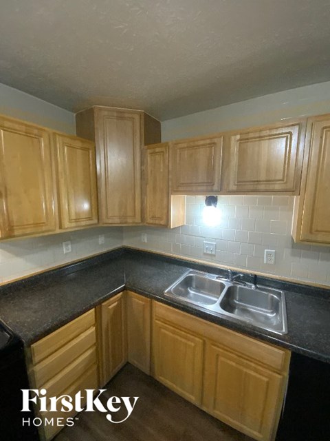 A kitchen with wooden cabinets and a black countertop.