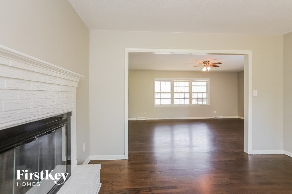 an empty living room with a fireplace and a ceiling fan