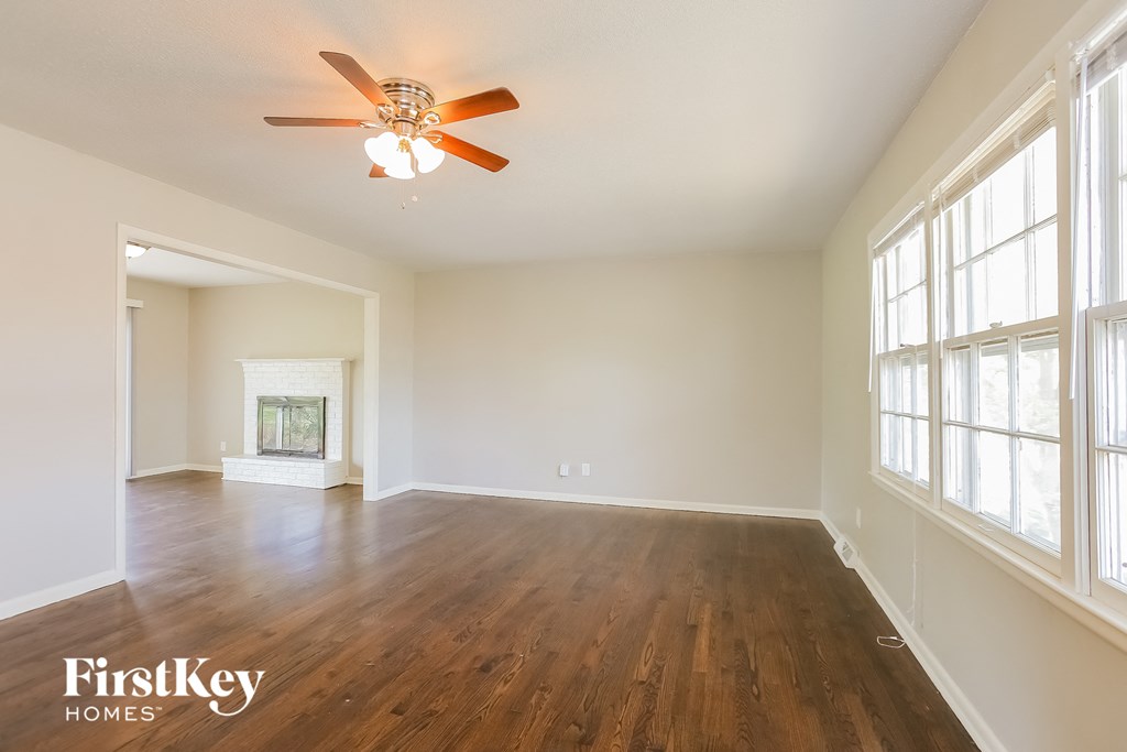 an empty living room with wood floors and a ceiling fan