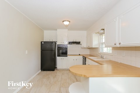 a kitchen with white cabinets and a black refrigerator