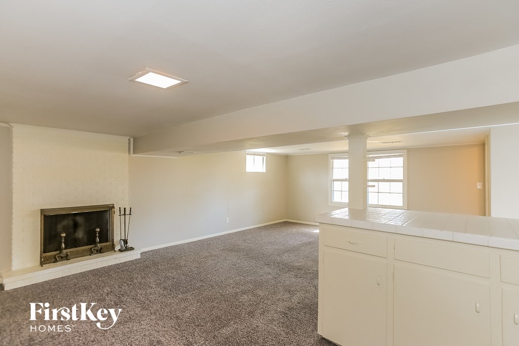 an empty living room with a fireplace and white cabinets