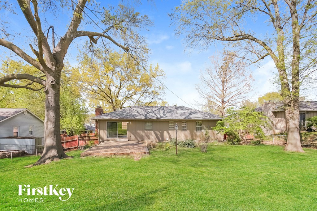 a backyard with a house and a green lawn and trees
