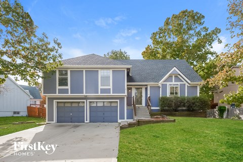 A blue house with a white garage door is for sale.