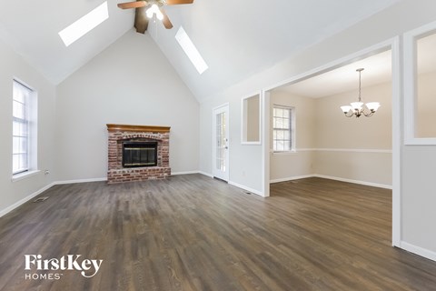 A spacious room with a fireplace and wooden floors.