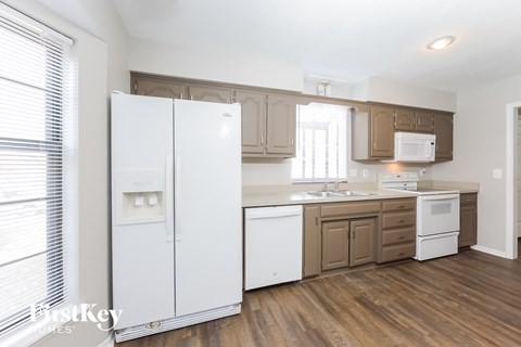 A kitchen with white appliances and wooden floors.