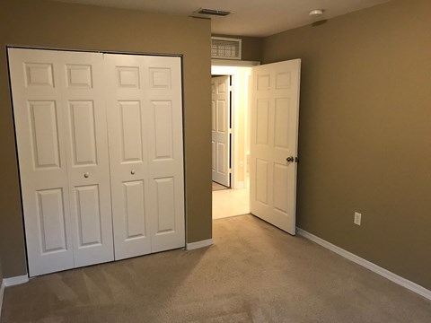 a bedroom with two closets and two doors and a carpeted floor