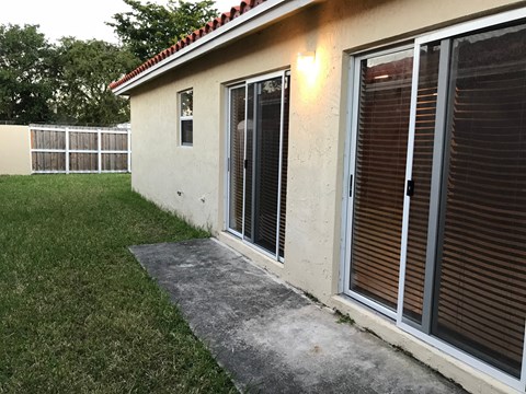 a side view of a house with sliding glass doors and a concrete walkway outside