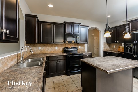 a kitchen with black cabinets and granite counter tops and a sink