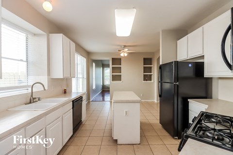a kitchen with white cabinets and a black refrigerator