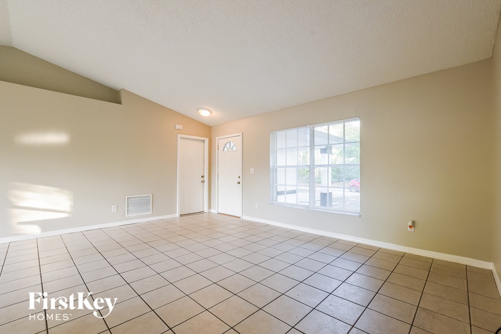 A spacious empty room with tile flooring and a large window.