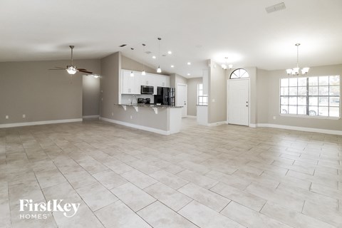 A spacious living room with a kitchen in the background.