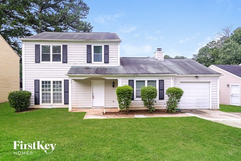 A white house with a black roof and a small front yard.