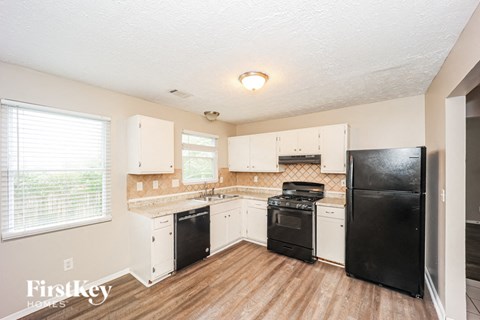 A kitchen with black appliances and wooden floors.