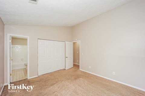 A bedroom with a carpeted floor and a white door.