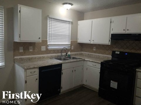 A kitchen with white cabinets and a black dishwasher.